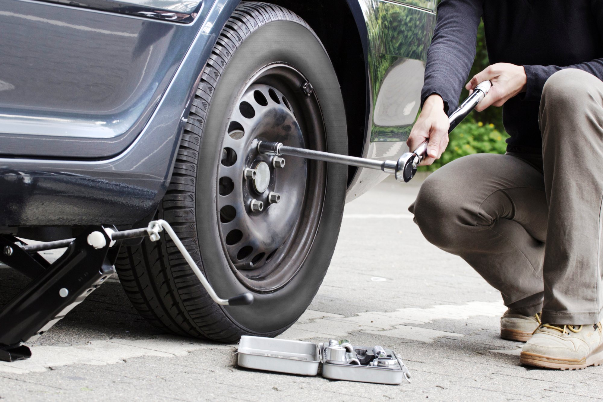 Person using wrench to check tire pressure on vehicle wheel